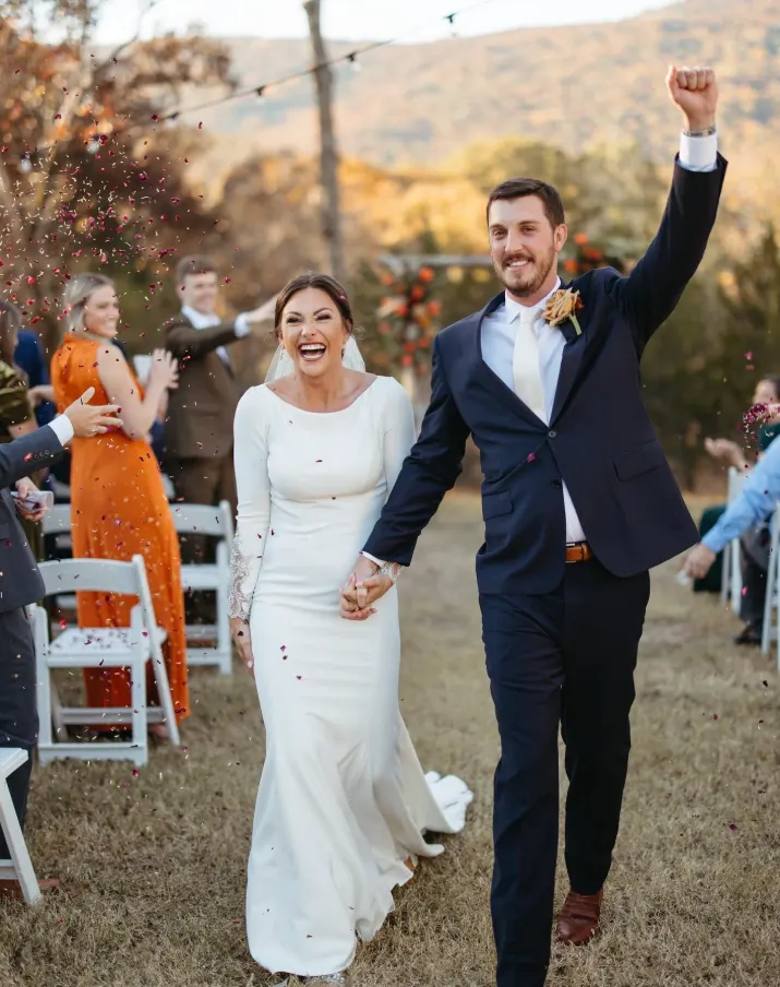 Newlyweds walking back up the aisle as their guests cheer